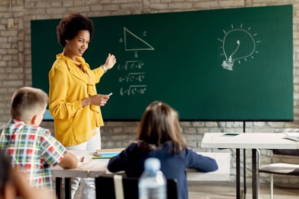 teacher at chalkboard with student at desk